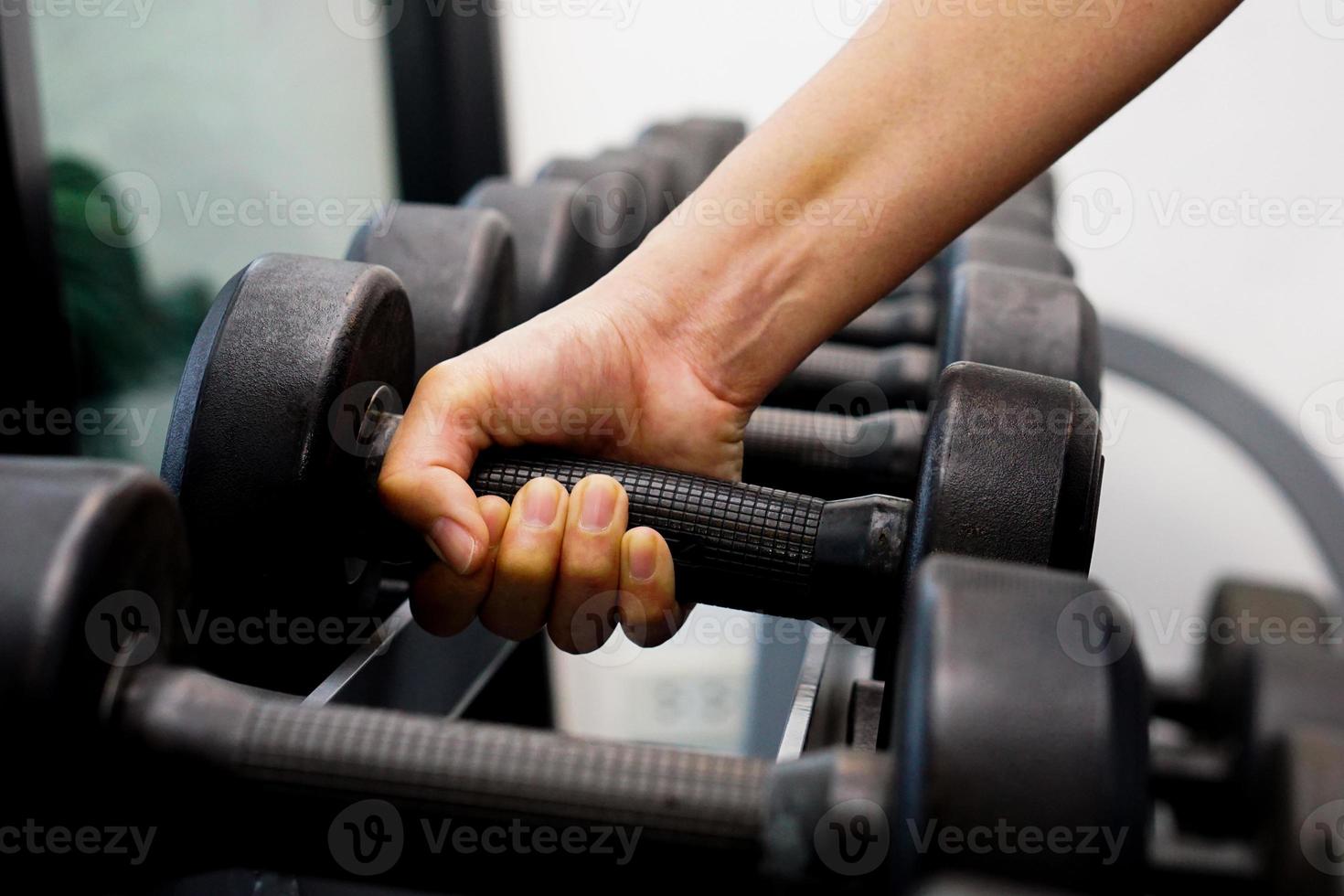 närbild av hand som håller hantel i fitness. foto