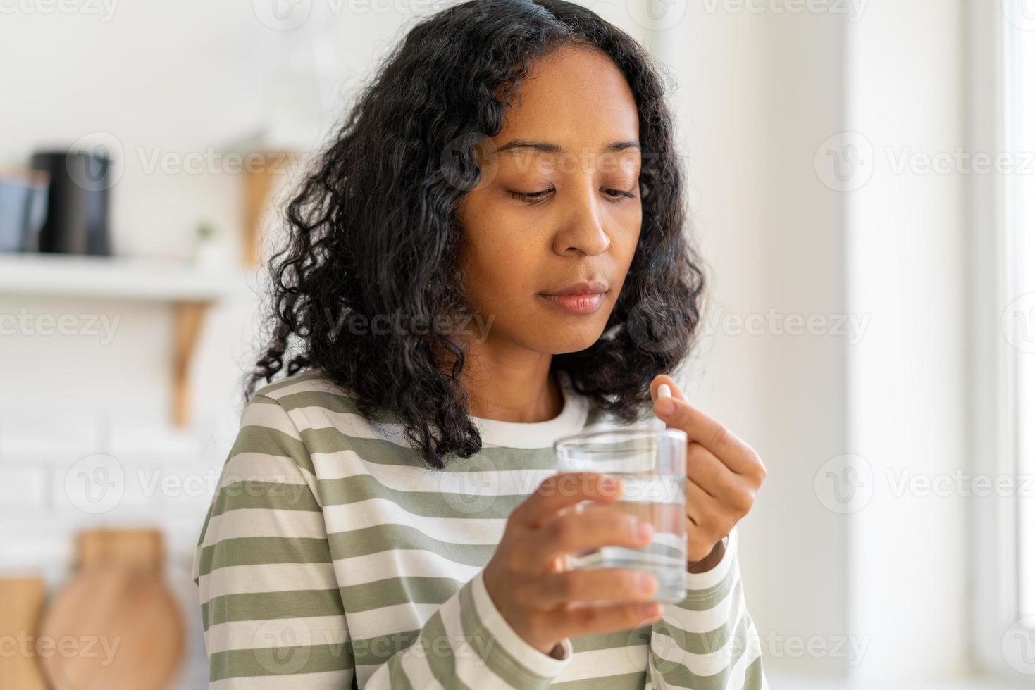 afroamerikanska kvinnliga tvätta ner piller med ett glas water.healthy tillägg åtgärda behandling foto