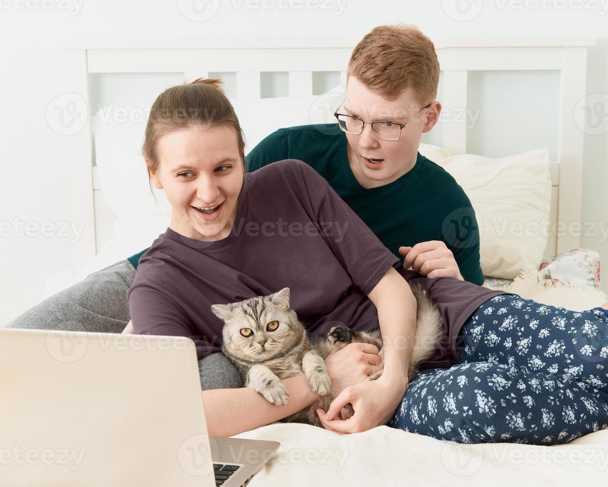 kär tonåring liggande på sängen, titta på filmer på bärbar dator under karantän på grund av coronavirus-pandemin foto