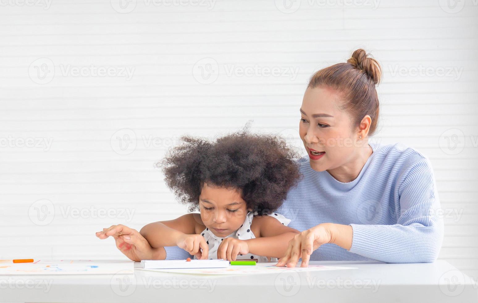 dotter och mor tillsammans målar, mor och barn dotter ritar är engagerade i kreativitet i vardagsrummet foto