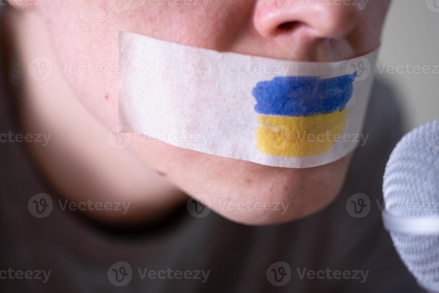 tejpa över hans mun med ukrainska flaggan, försöker tala i en mikrofon. foto