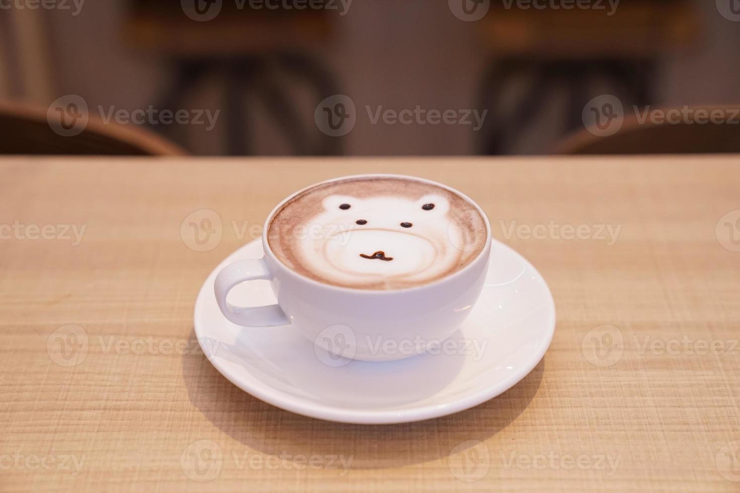 söt björn latte hett kaffe i vit kopp på träbord, läs för att servera. foto