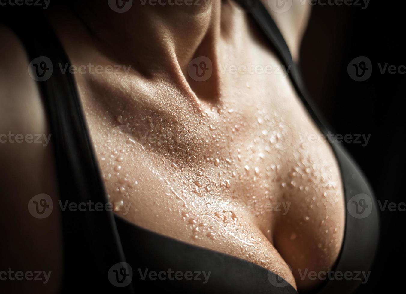 kvinna i svart bh, med våt hud på svart bakgrund foto
