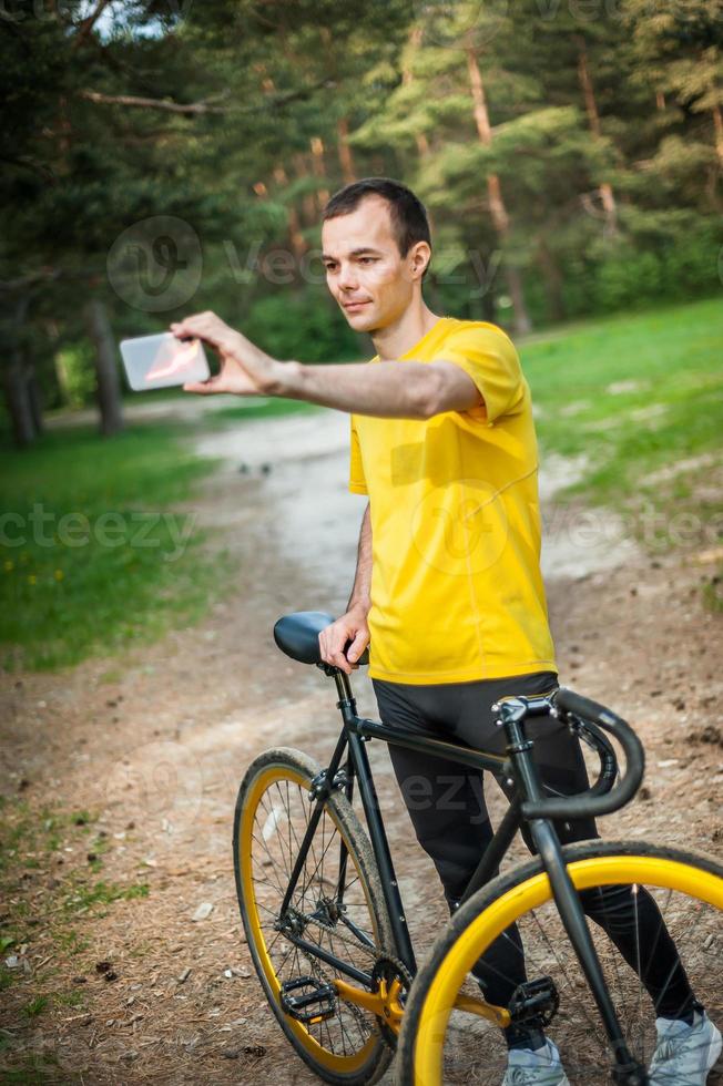 en ung man som tar en selfie med sin cykel. foto