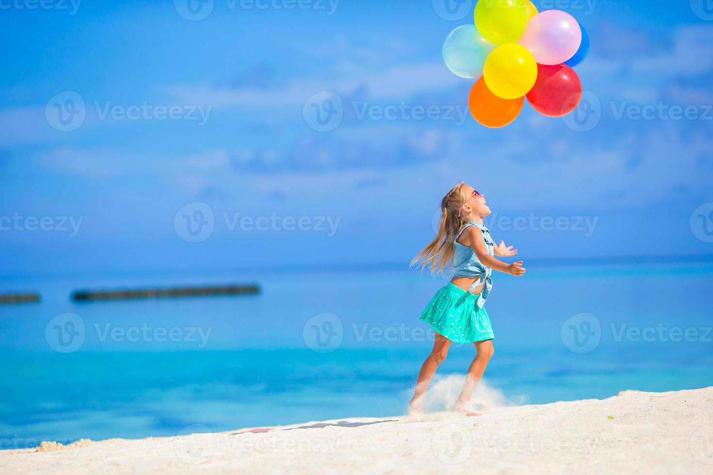 bedårande liten flicka som leker med ballonger på stranden foto