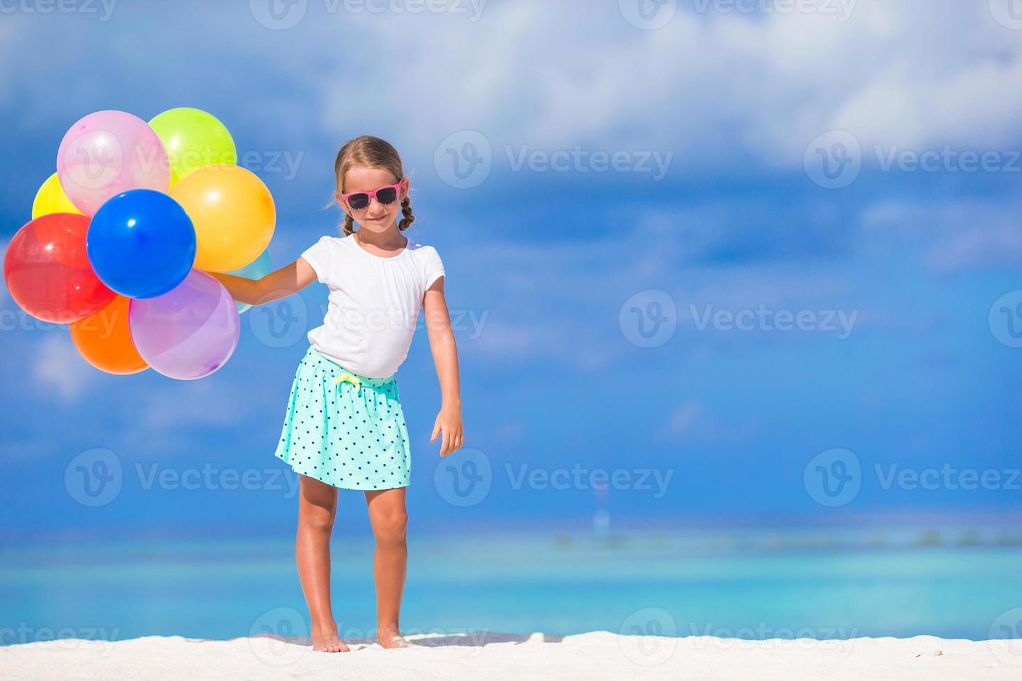 bedårande liten flicka som leker med ballonger på stranden foto