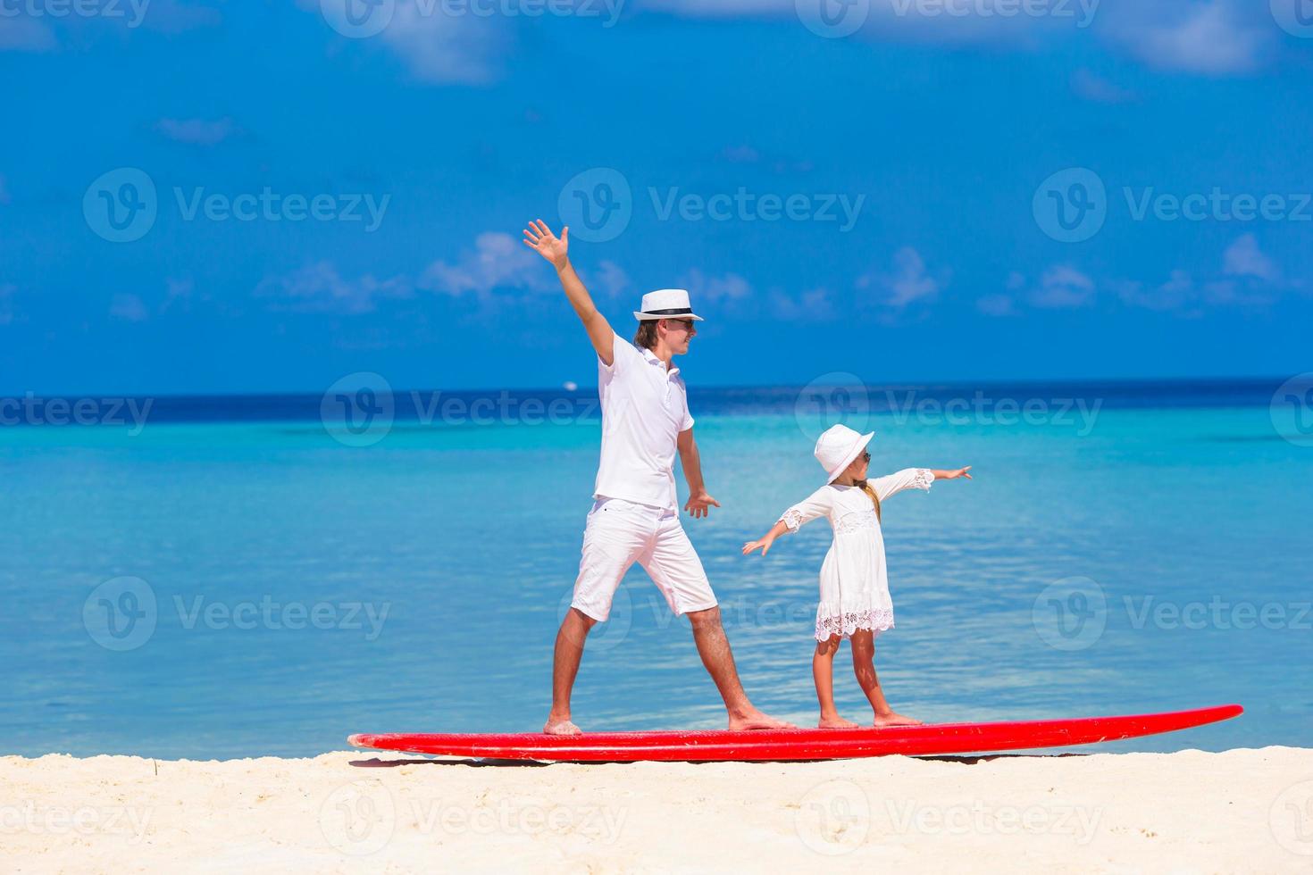 far med lilla dotter på stranden tränar surfposition foto