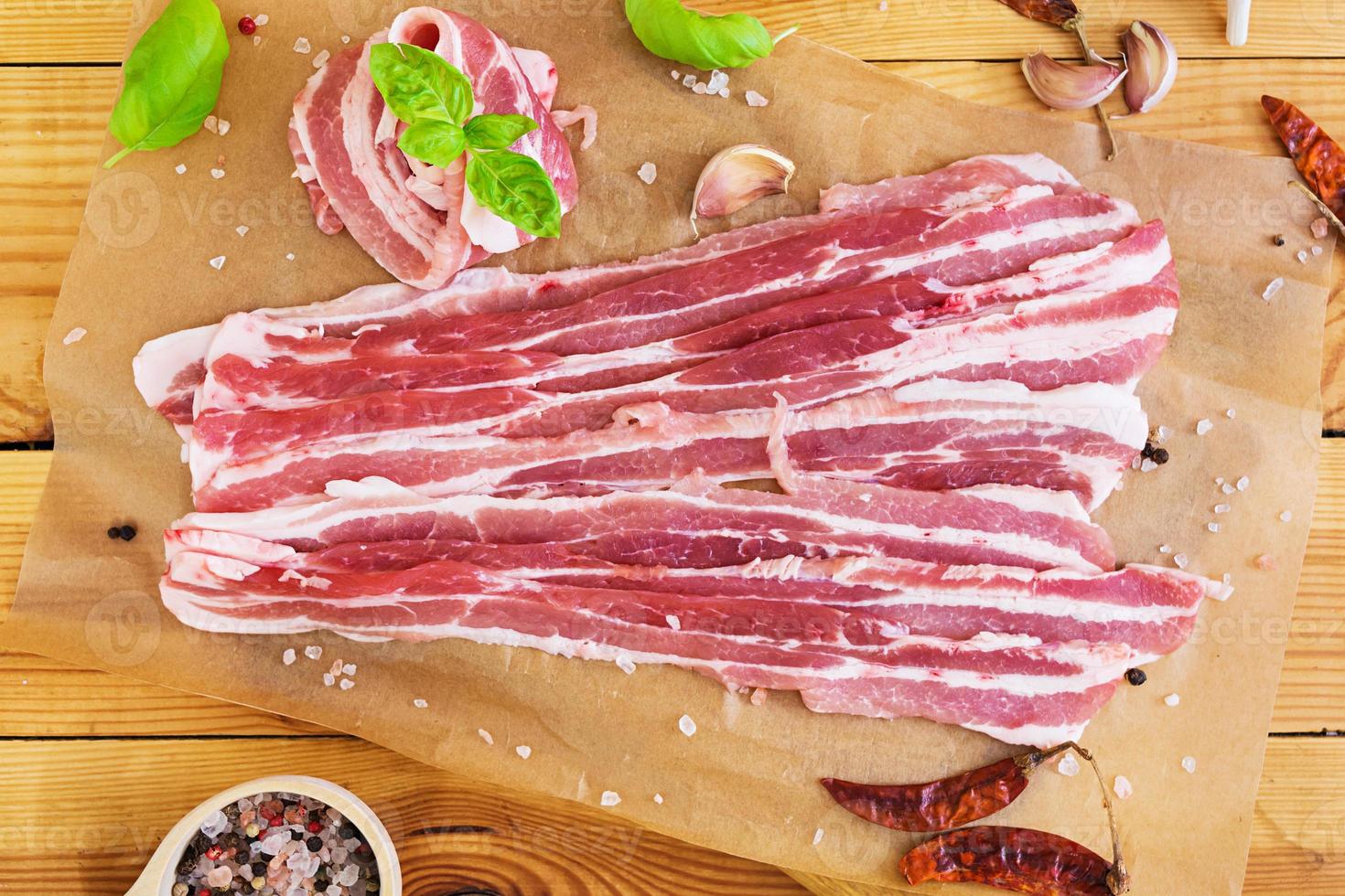 färsk skivad bacon med kryddor på vit bakgrund foto