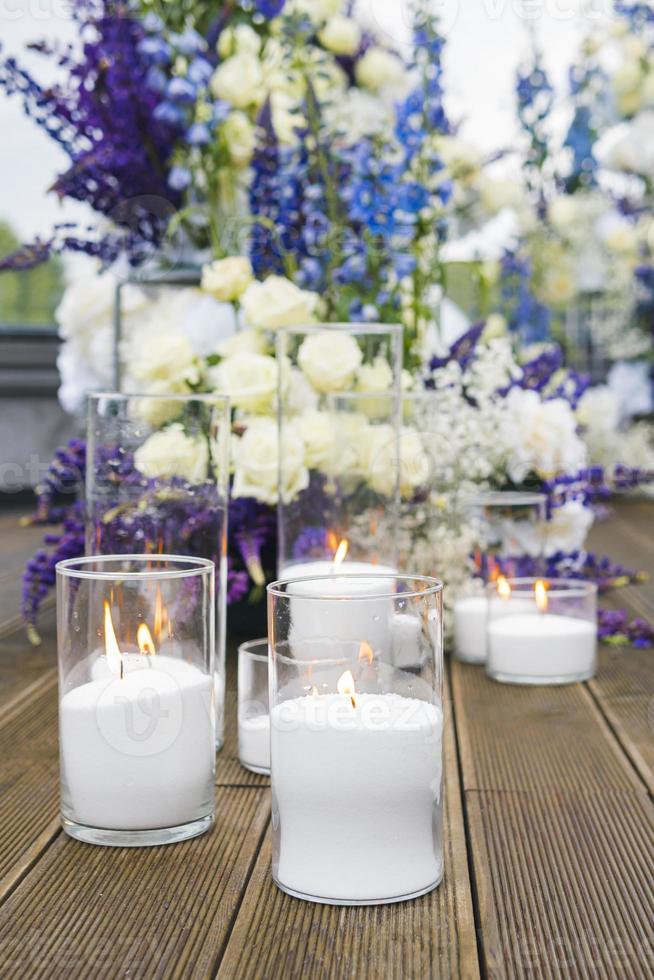 närbild av vita ljus på bröllopsmottagning med vit, blå och violetta blomma, utomhus. elegant lyx bröllop dekoration sammansättning på ceremoni plats foto