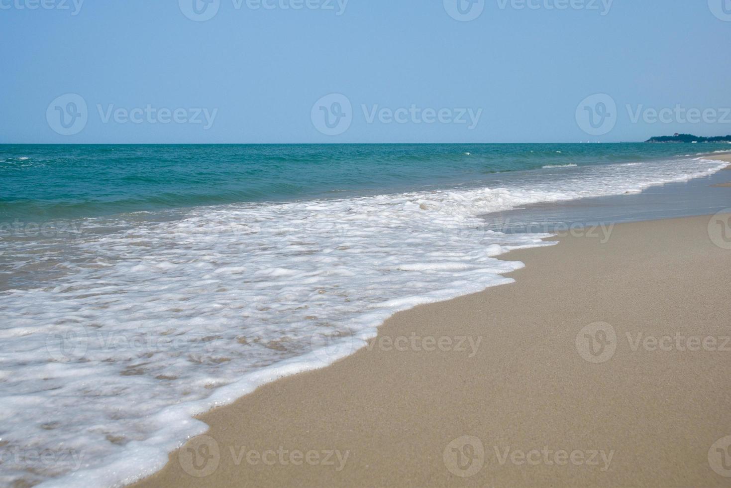 vidvinkel skott av havsvatten som träffar stranden, vit svamp av havet, sommar natur bakgrundsbild koncept. foto