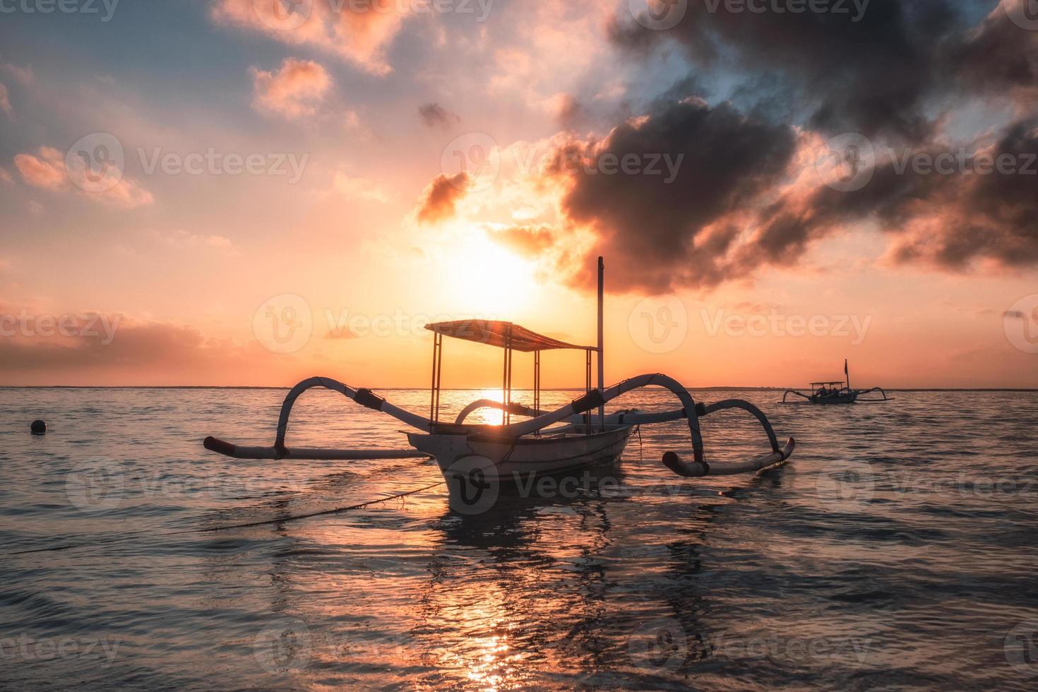 gammal traditionell jukung fiskebåt på stranden vid färgglad soluppgång foto