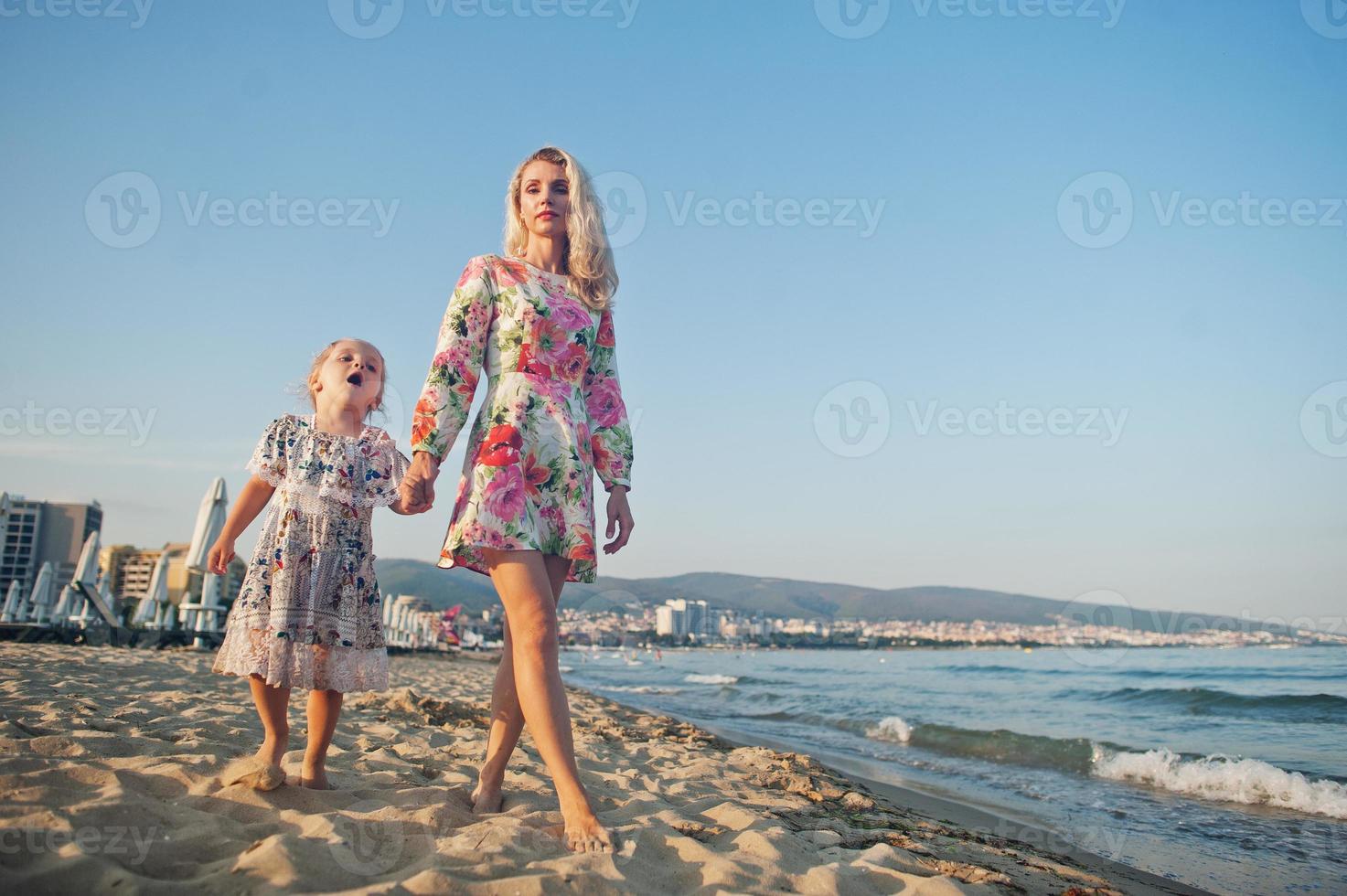 mor och vackra dotter ha kul på stranden. porträtt av glad kvinna med söt liten flicka på semester. foto