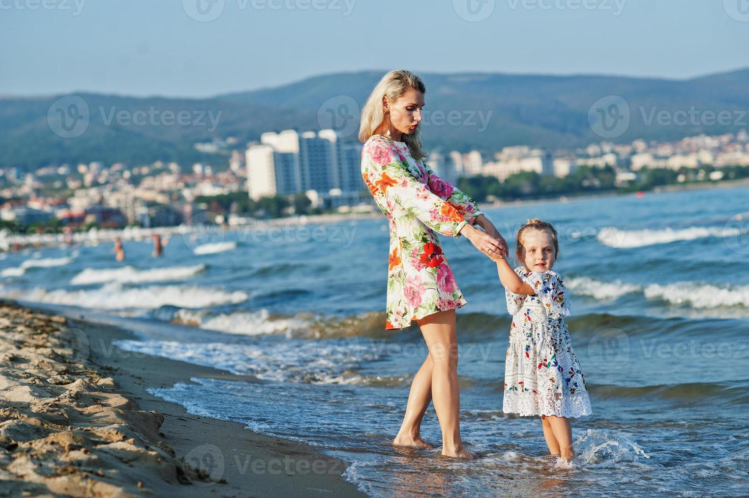 mor och vackra dotter ha kul på stranden. porträtt av glad kvinna med söt liten flicka på semester. foto