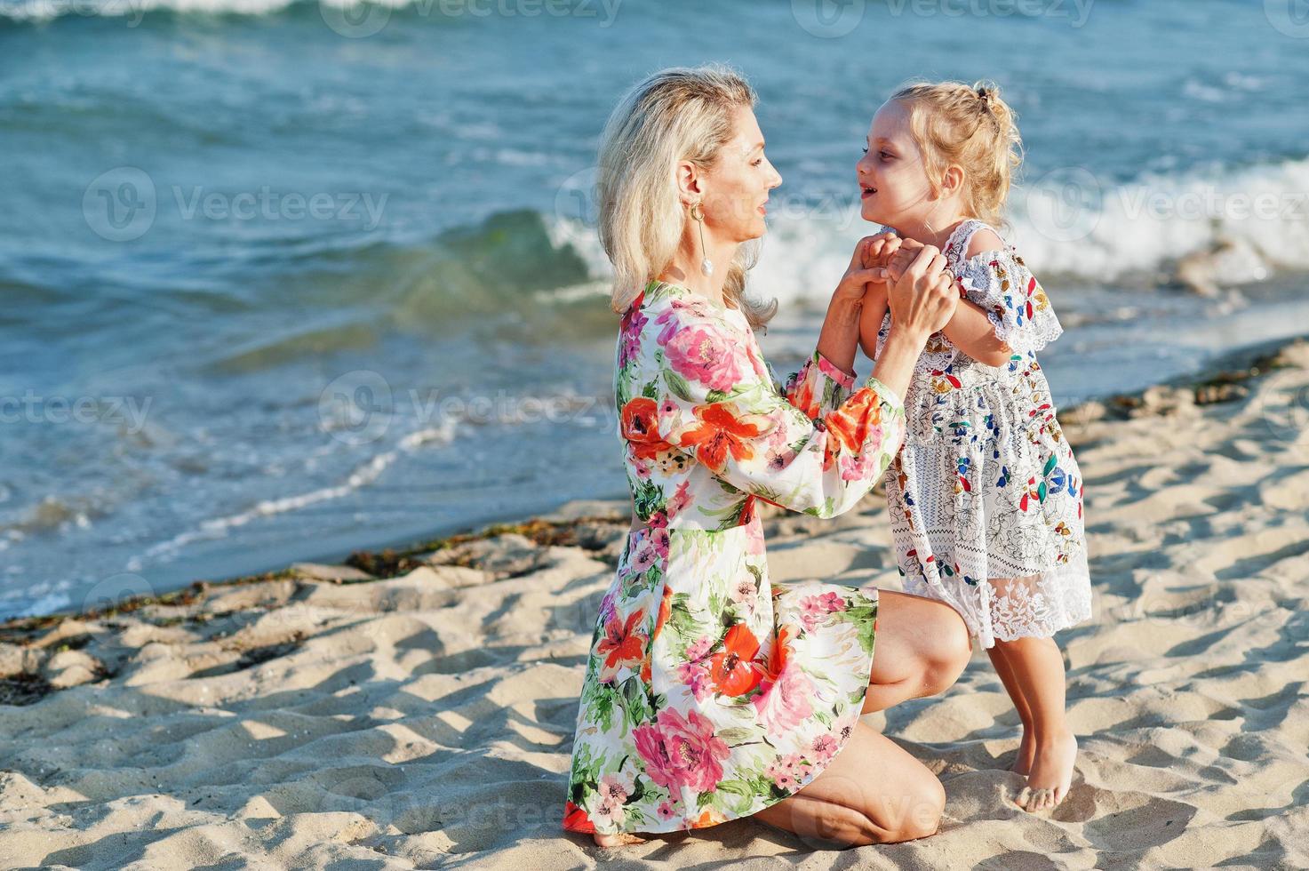 mor och vackra dotter ha kul på stranden. porträtt av glad kvinna med söt liten flicka på semester. foto