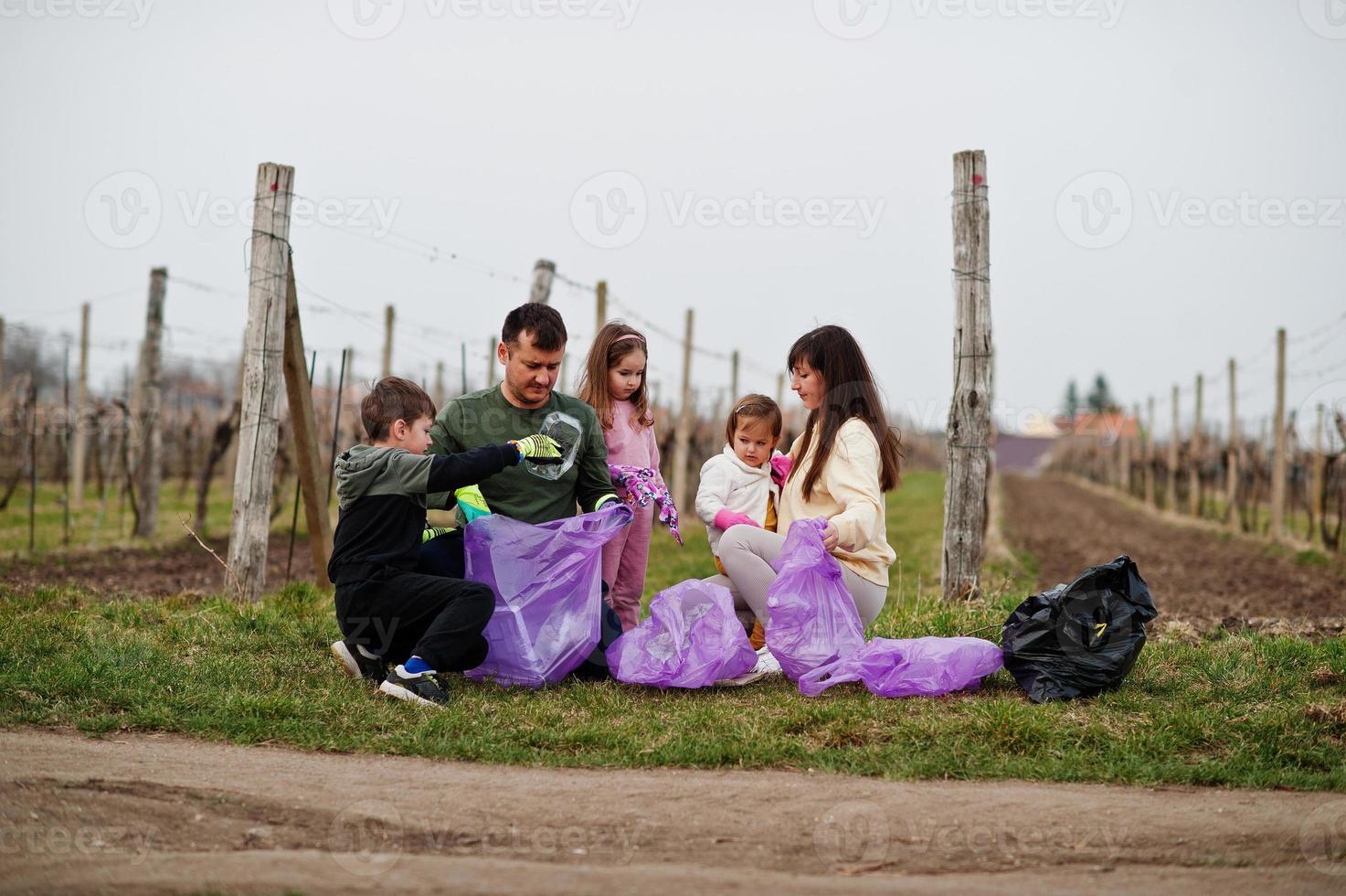 familj med soppåse som samlar sopor medan de städar i vingårdarna. miljövård och ekologi, återvinning. foto