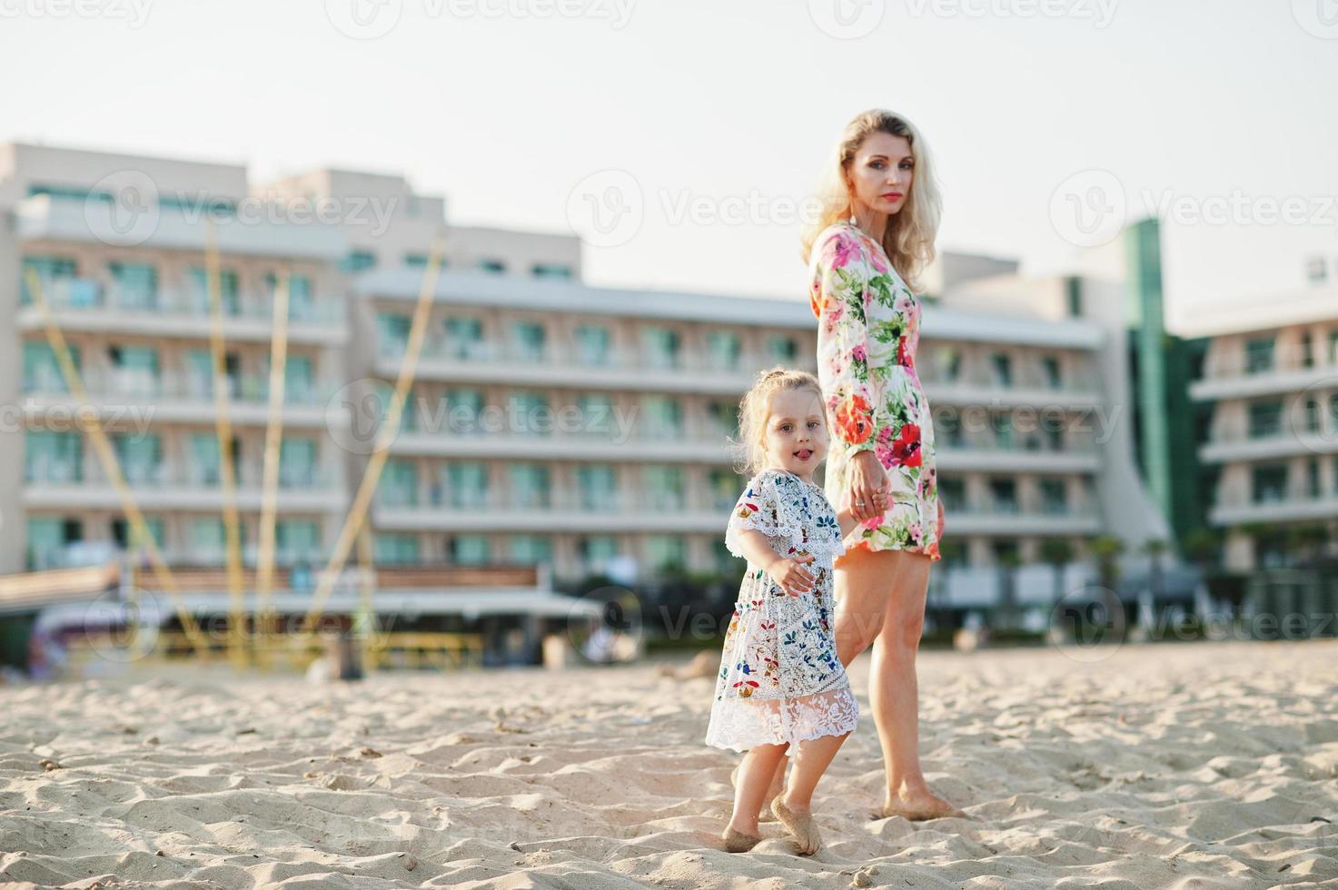mor och vackra dotter ha kul på stranden. porträtt av glad kvinna med söt liten flicka på semester. foto