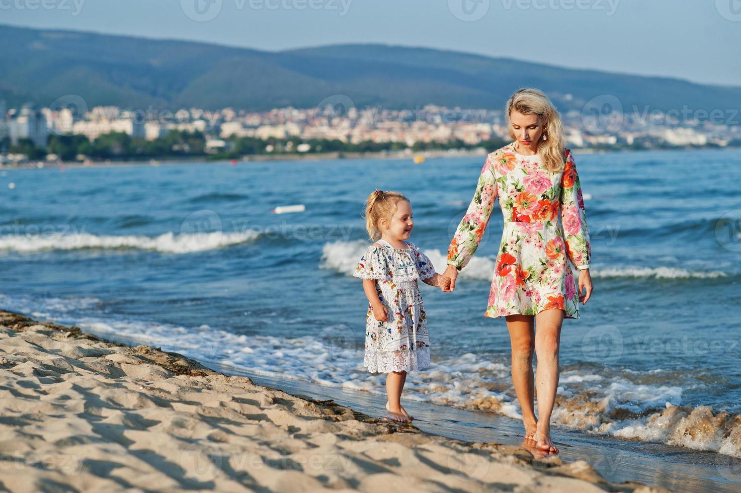 mor och vackra dotter ha kul på stranden. porträtt av glad kvinna med söt liten flicka på semester. foto