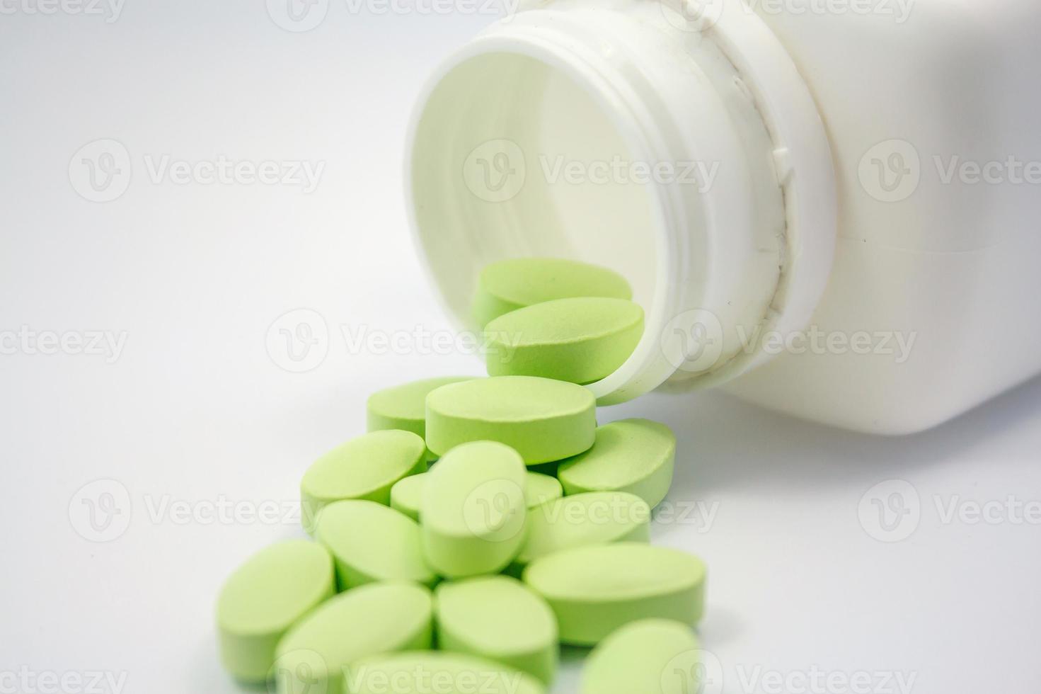gröna piller och piller flaska på vit bakgrund foto