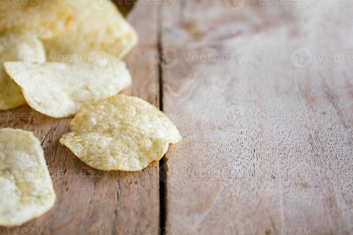 öppnat paket med läckra potatischips på träbord foto