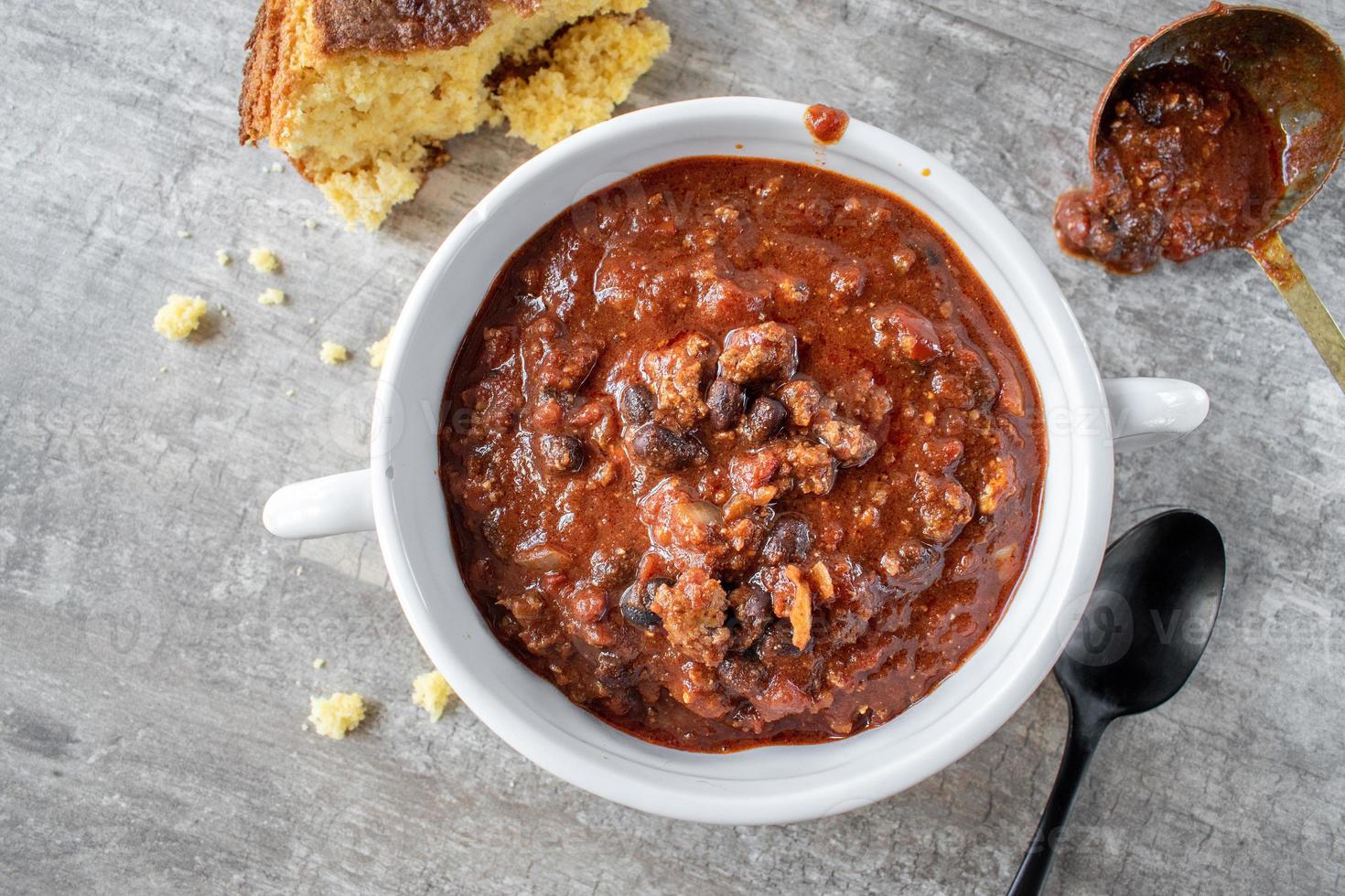 skål med chili med svarta bönor och majsbröd platt låg foto