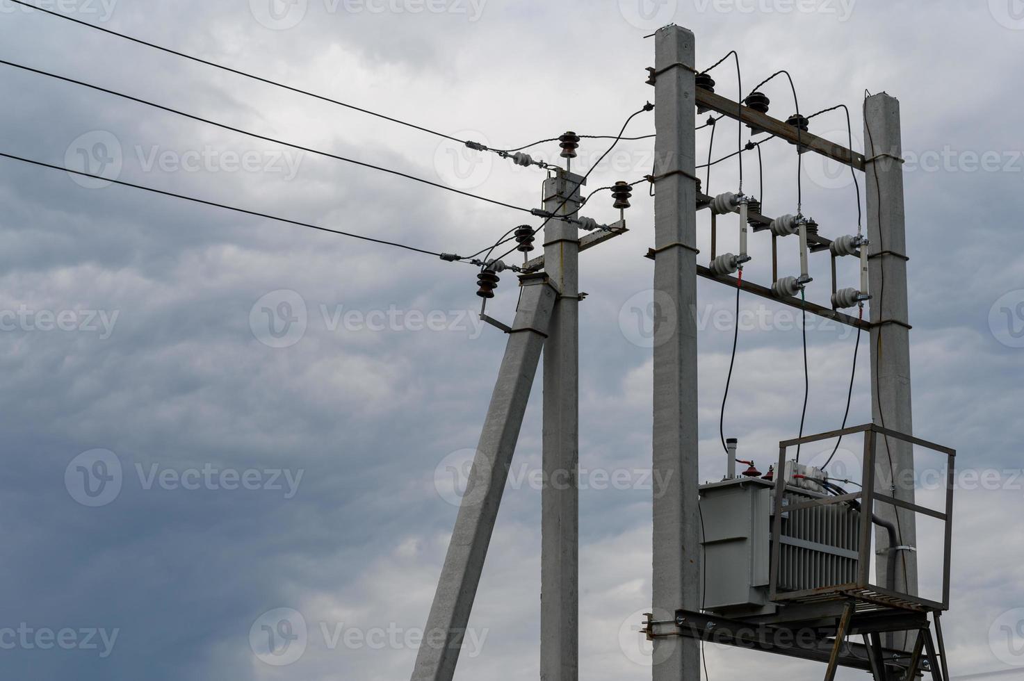 elektrisk transformator på stolpar mot en blå himmel. foto