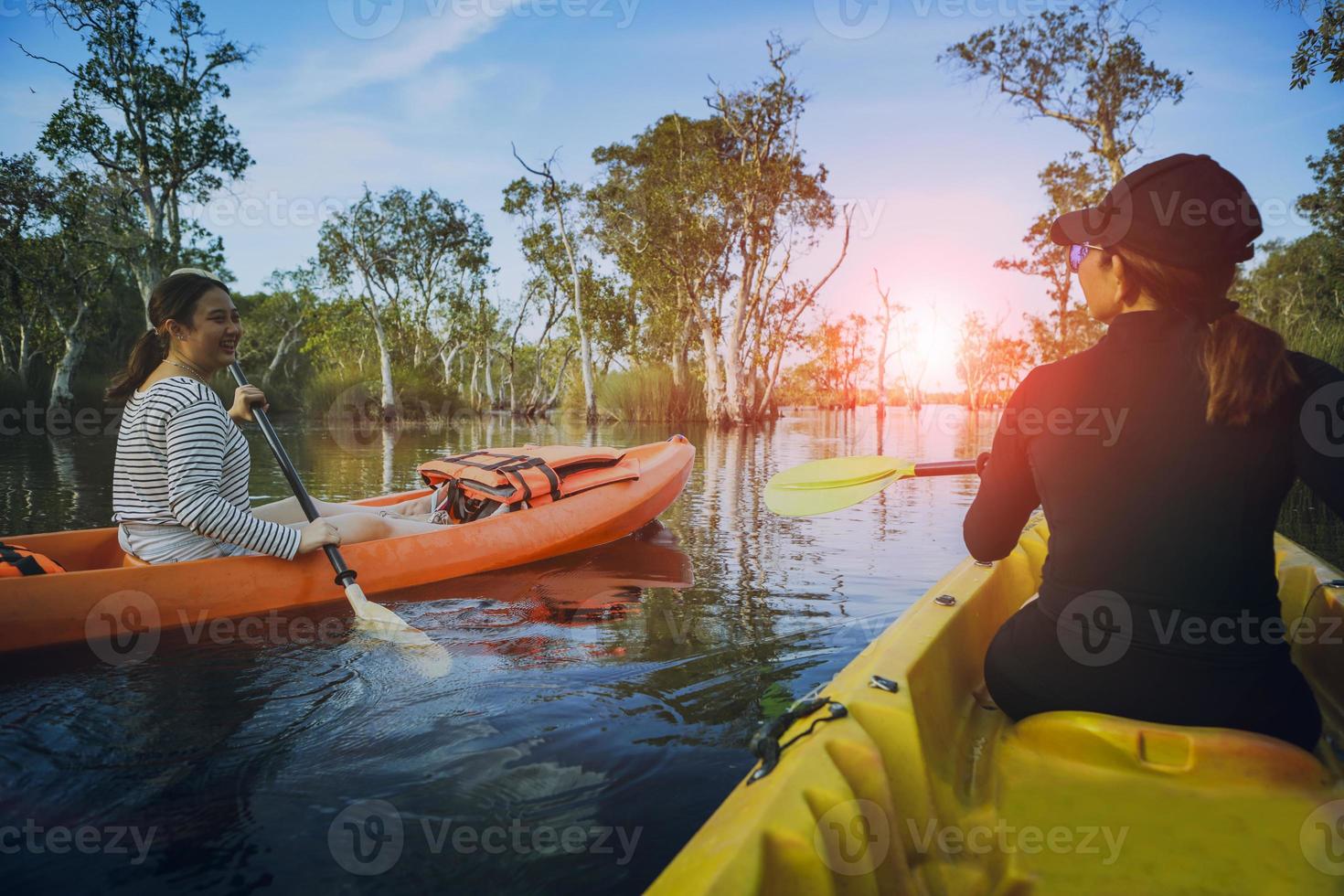 två asiatiska kvinnor seglar havskajak i mangrove lagunen foto