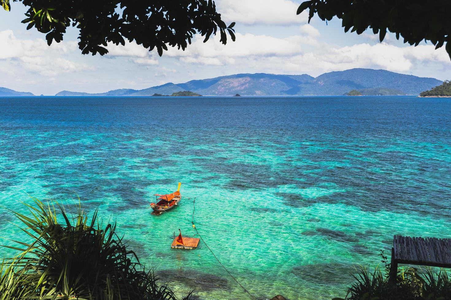 vackert sommarlandskap av tropisk ö med lång svansbåt i havet. foto
