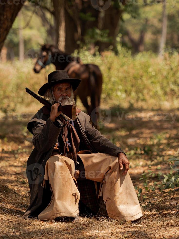 en gammal cowboy satt och rastade sin häst efter att ha arbetat hårt på ett lantbruksområde foto