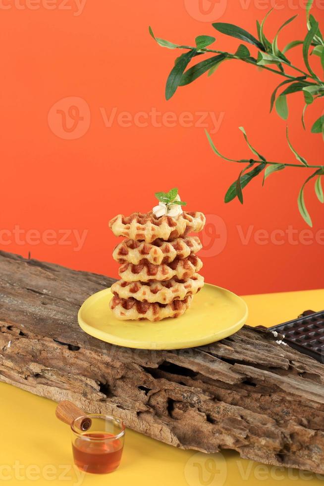 staplade croissantvåfflor i gult bord och orange bakgrund. croffle är viral tårta från Sydkorea. koncept pop färg mat, kopiera utrymme för text foto