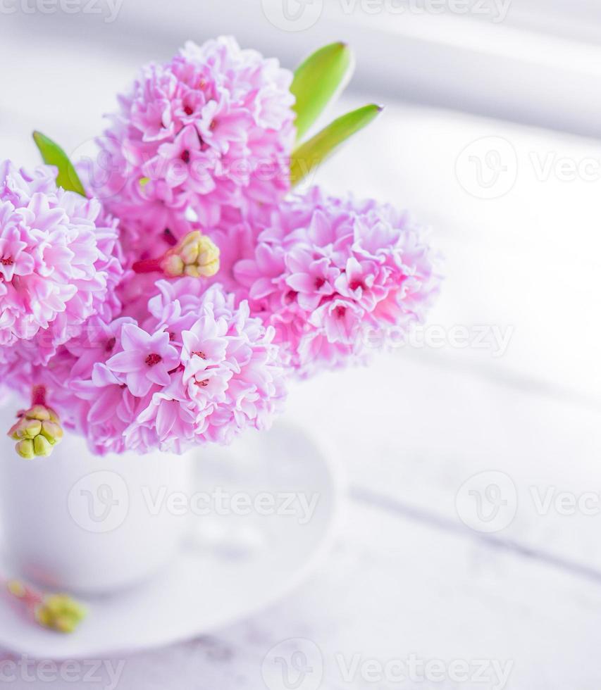rosa hyacinter i vit vas på vit bakgrund foto