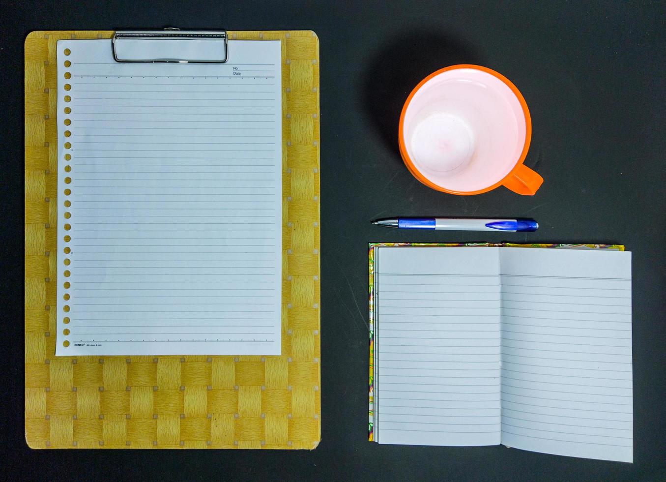 papper, bok, penna och en kopp mineralvatten på en svart bakgrund foto