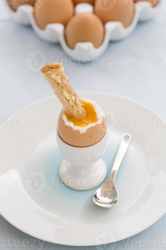 mjukt kokt ägg i äggkoppen med rostat bröd på bordet foto