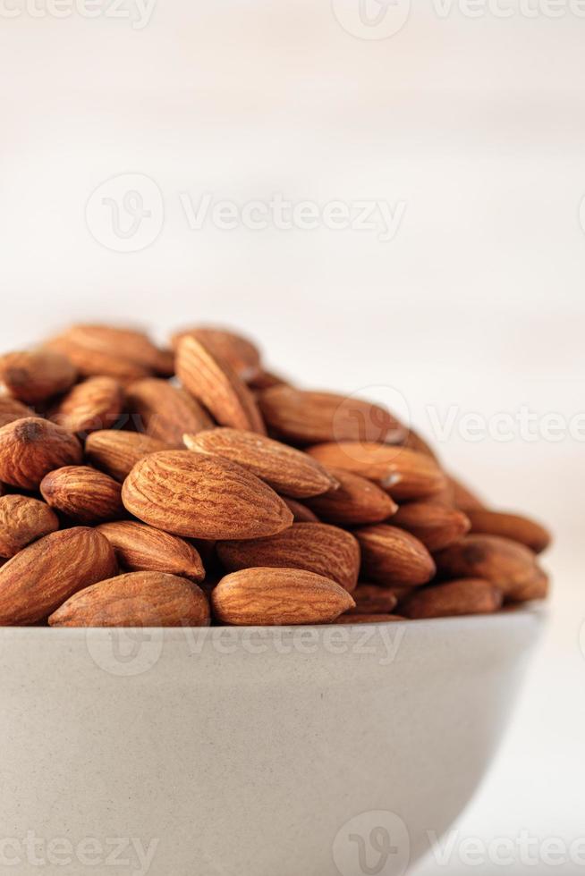 mandlar i keramisk skål på vitt trä table.organic diet råmaterial foto