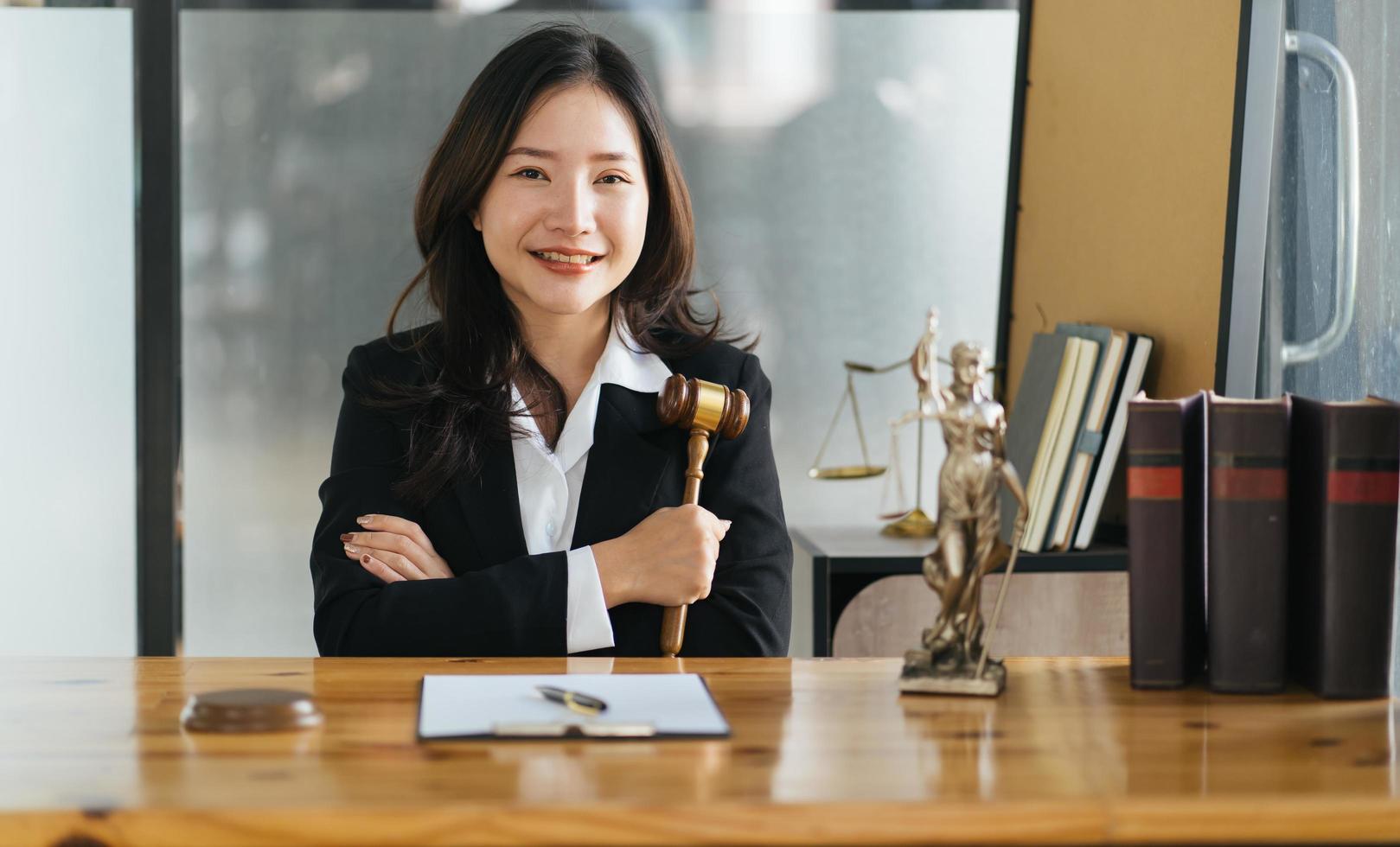 seriös kvinnlig asiatisk advokat med leende sitter på arbetsplatsen och tittar på kameran foto