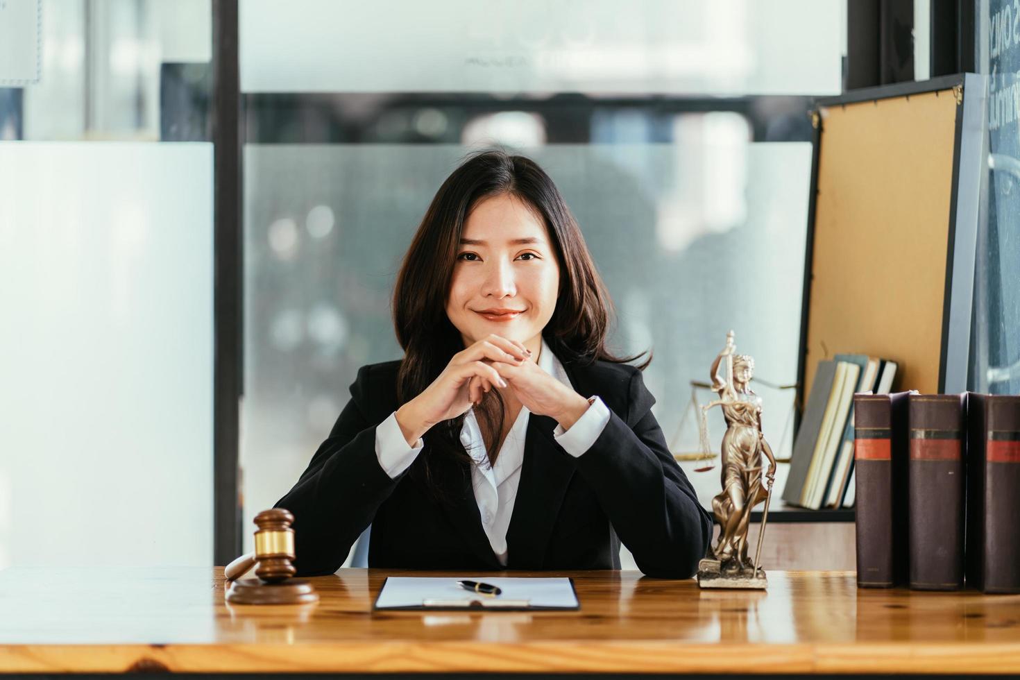 seriös kvinnlig asiatisk advokat med leende sitter på arbetsplatsen och tittar på kameran foto