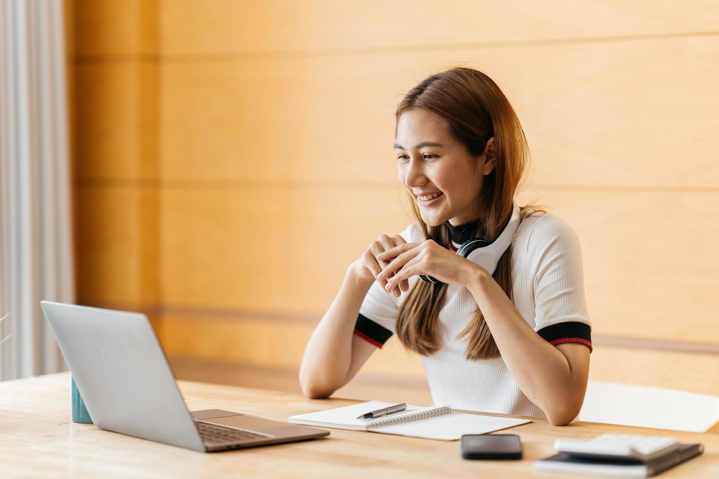 ung attraktiv asiatisk kvinnlig anställd bär hörlurar lyssna på digitala onlinekursutvecklingsprogram i karantän social distans i hemmet reskill upskill skolklass för karriärväg. foto