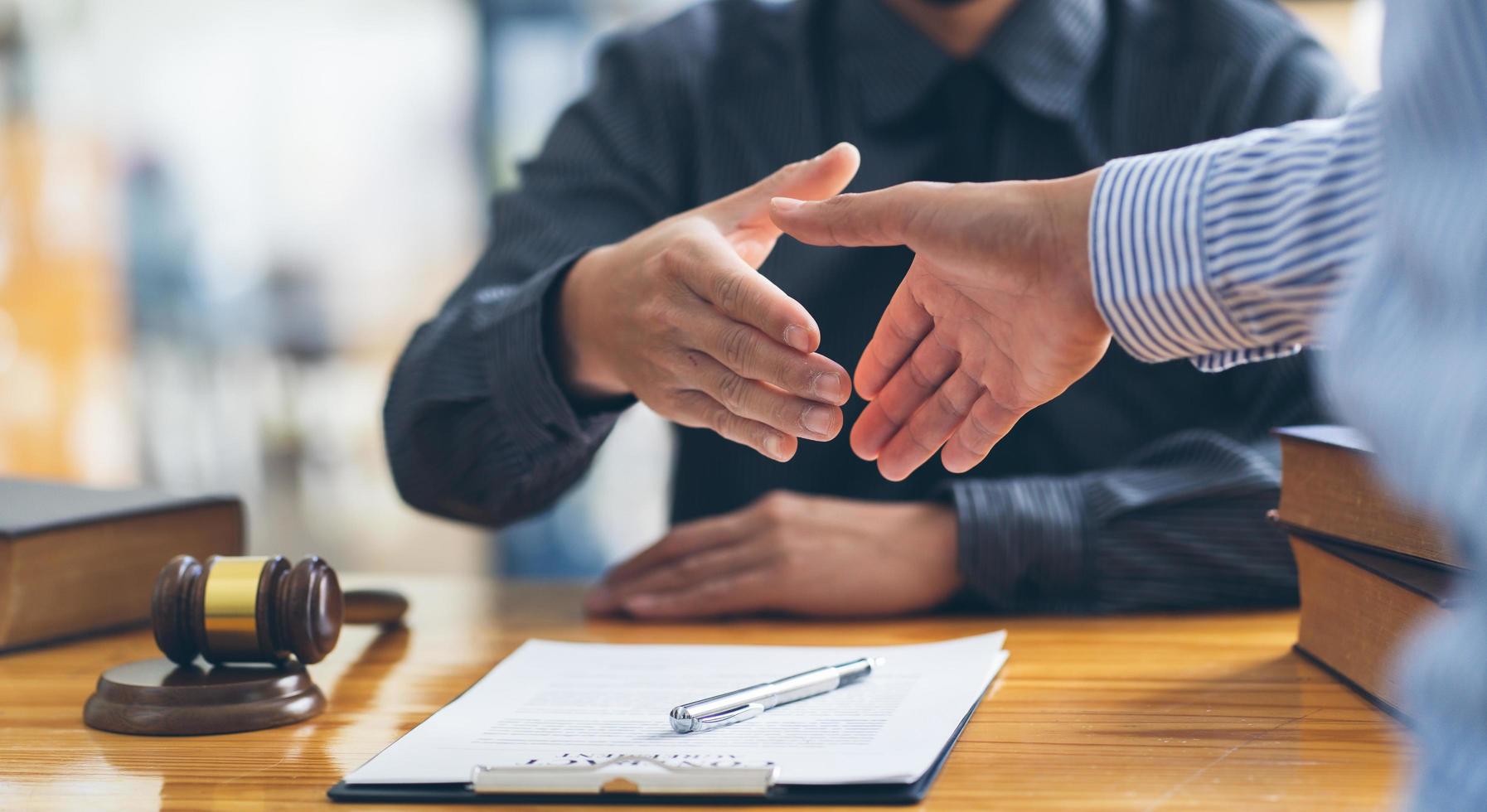 handslag efter gott samarbete, affärskvinna skakar hand med professionell manlig advokat efter att ha diskuterat en hel del kontrakt i rättssalen, rättsbegrepp, domareklubba med rättvisa. foto