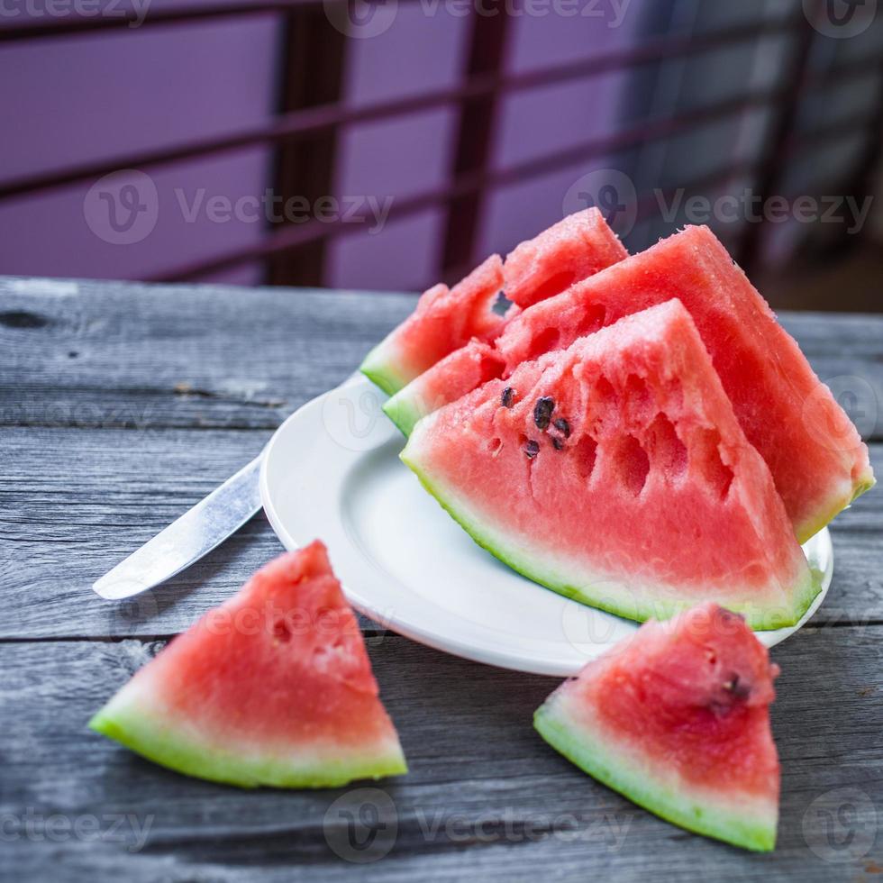 skivor vattenmelon på en tallrik på en träbakgrund foto