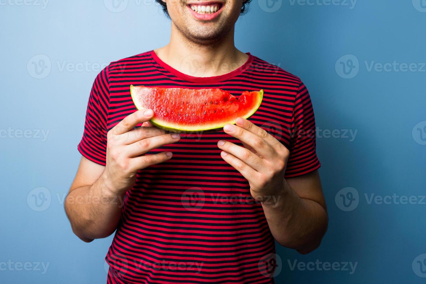 ung multiracial man med en skiva vattenmelon foto