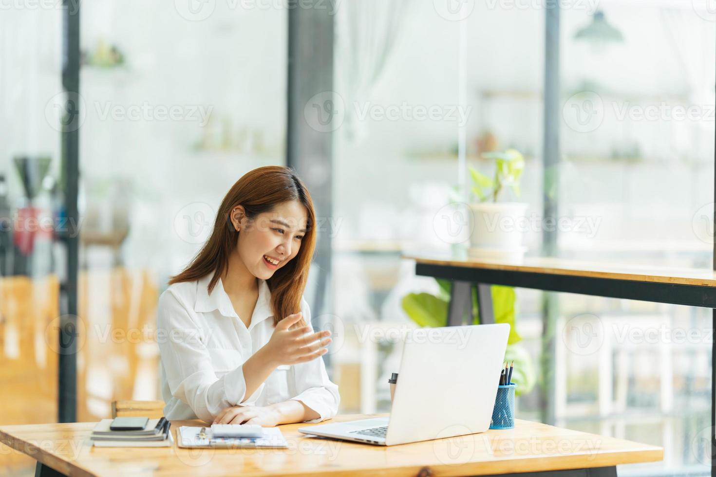 porträtt av asiatisk ung kvinna som arbetar på bärbar dator och finansiell rapport på kontoret. foto