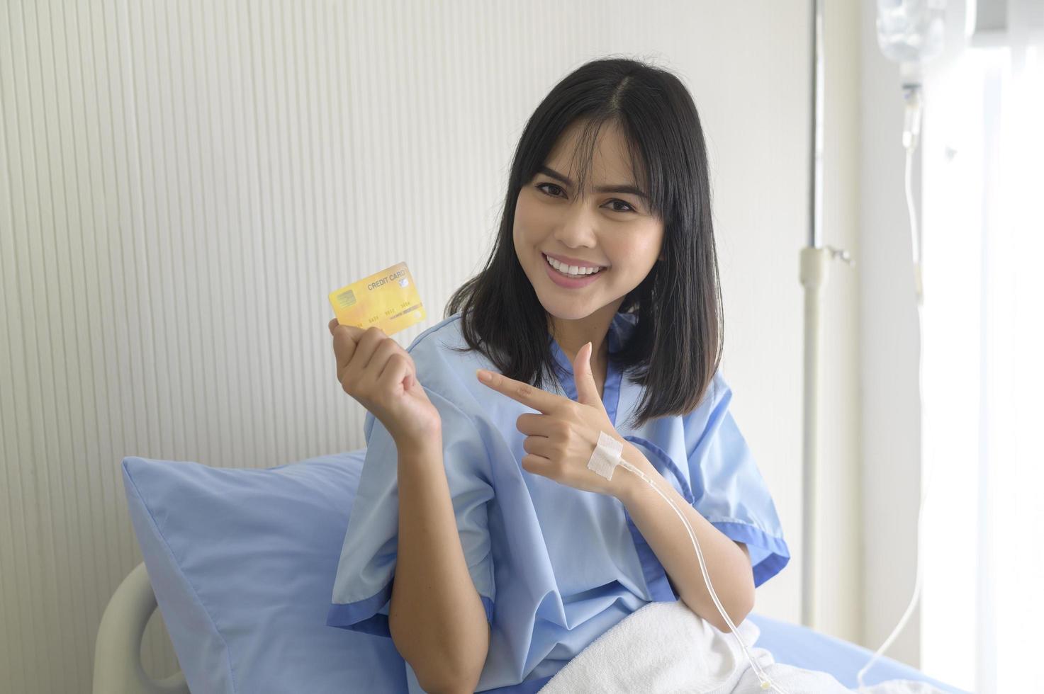 en ung patient kvinna håller kreditkort, erkännande på sjukhus, hälso-och sjukvård koncept foto