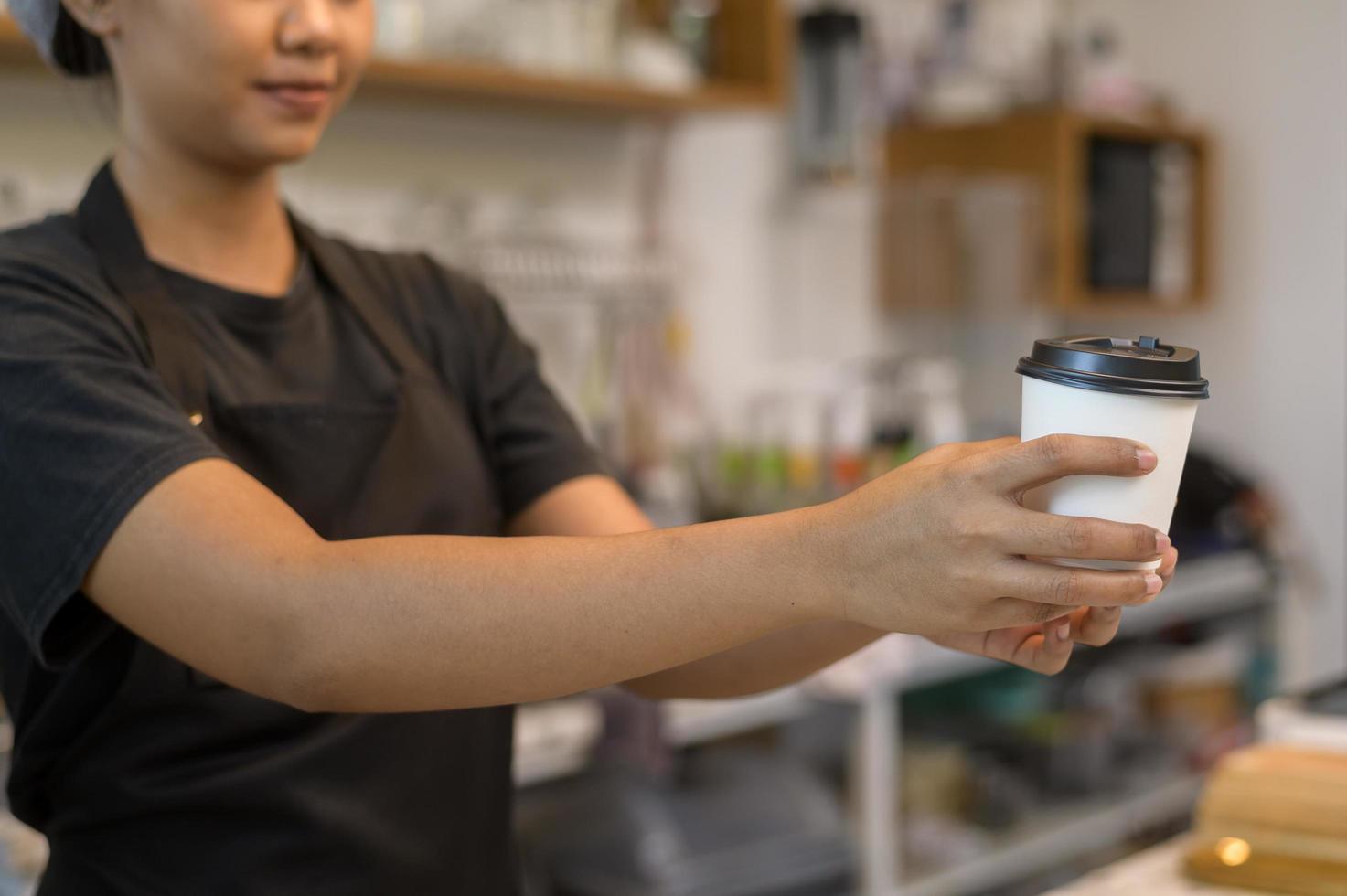 ung serviceinriktad baristakvinna som arbetar i kafé foto