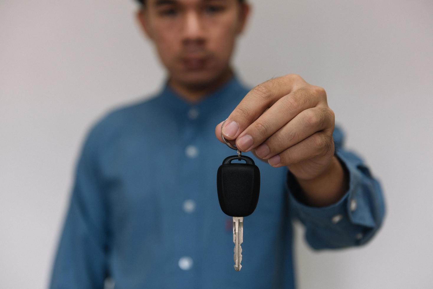 närbild händer som håller bilnycklar. man håller nyckeln till bil ger till agent för försäkring för försäljning. affärsinvestering försäkring bil beslag och bil koncept. foto