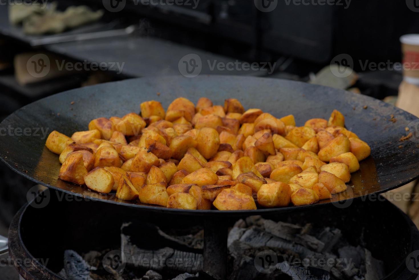 bitar av stekt potatis i en stor stekpanna under street food festivalen. foto