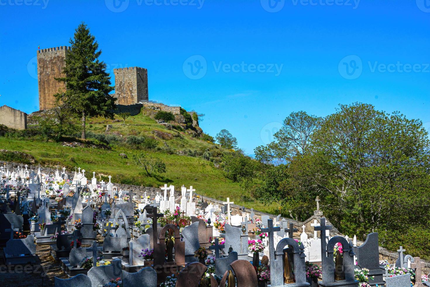 utsikt från toppen av kullen med ruiner i bakgrunden vid en kyrkogård längst fram foto
