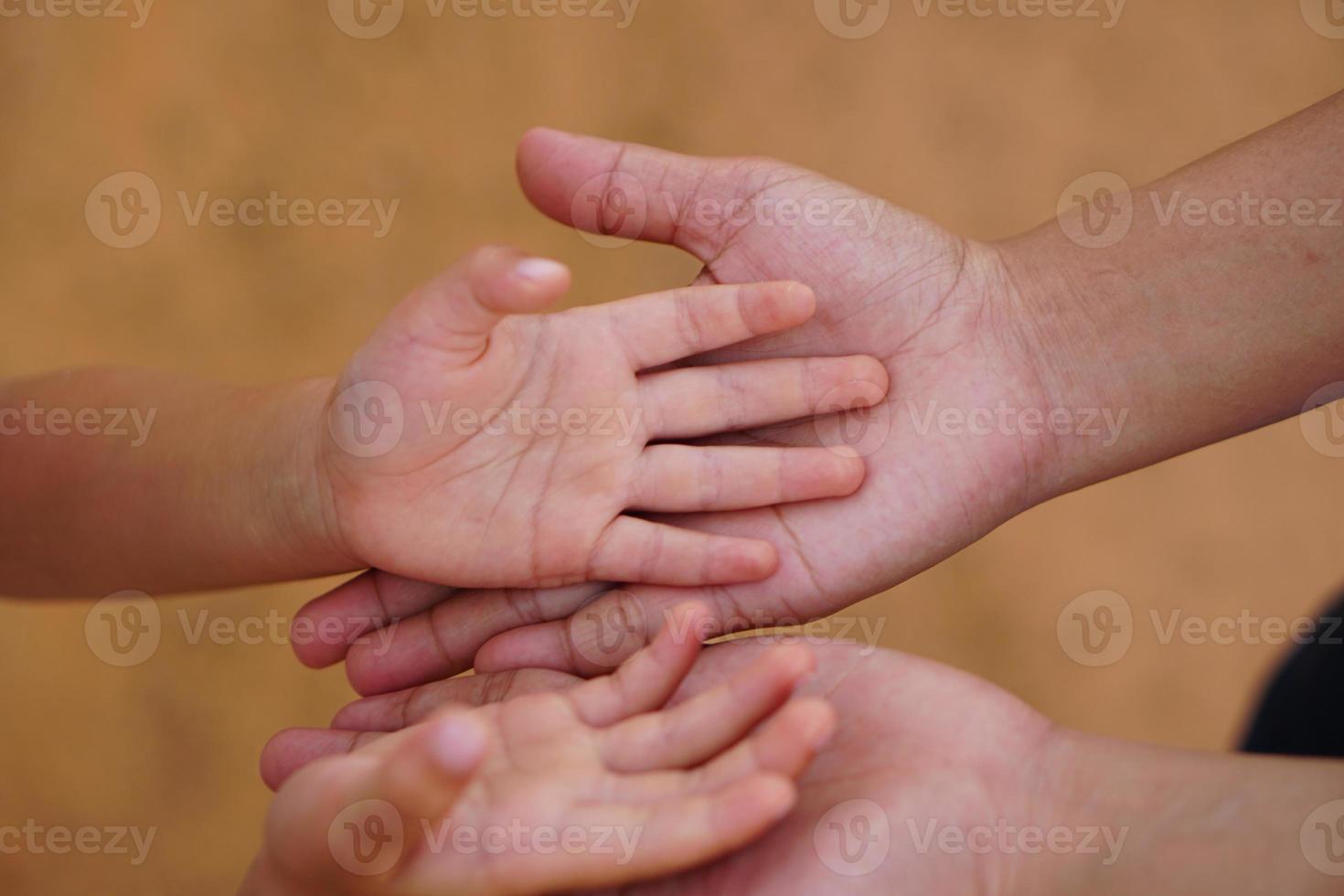 mor och barn håller varandra i hand för att ta emot något foto