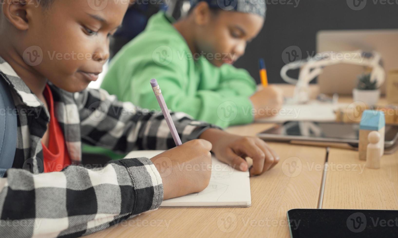 student i internationell förskola skriver en bok tillsammans i grundskoleklass, elever tycker om att studera i klassrummet. foto