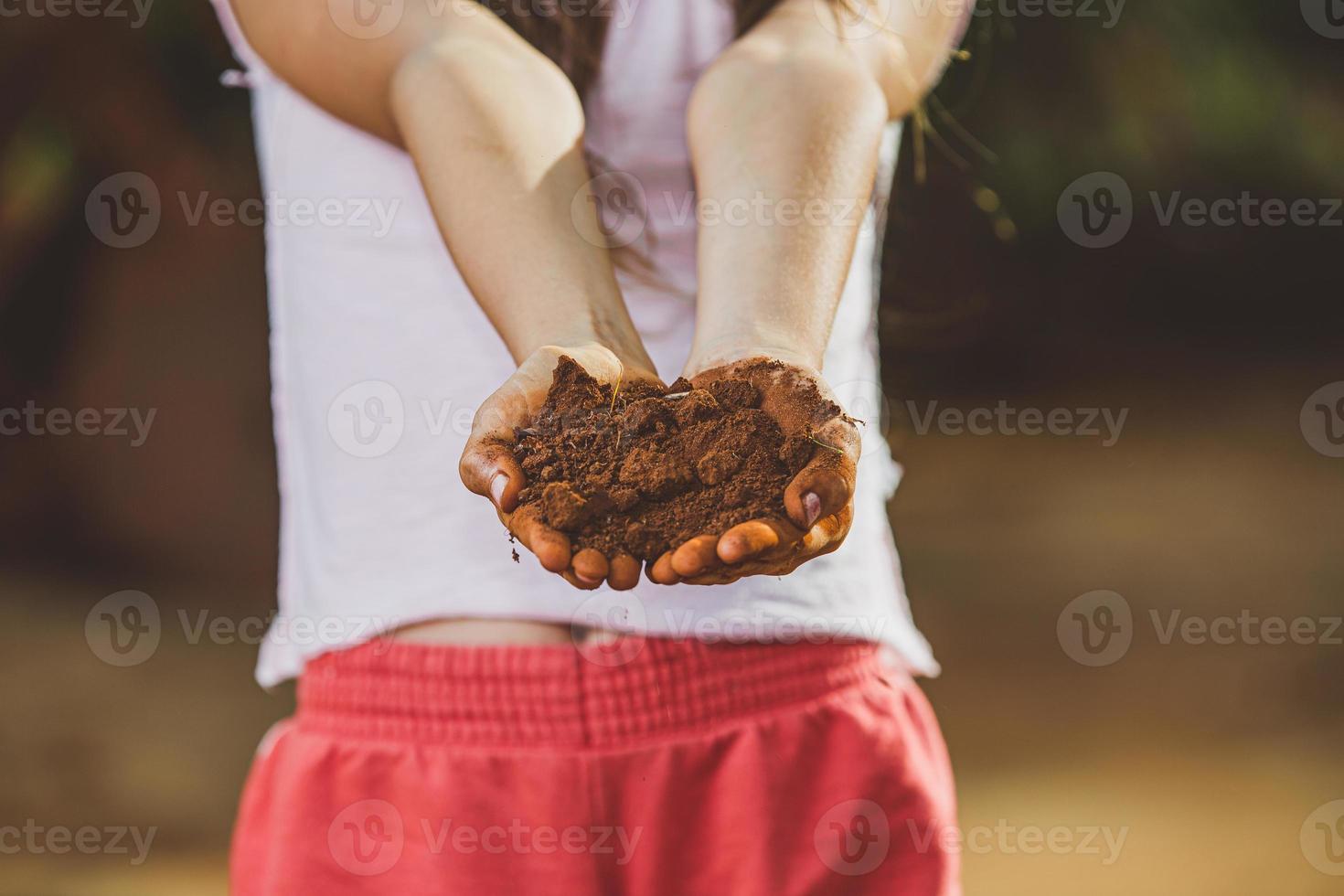 barn hand som håller jorden, förbereda för att plantera trädet. jordbrukare med jord i händerna, kvalitetskontrollkoncept, jordbruksföretag, livsmedelsodling. barn. foto