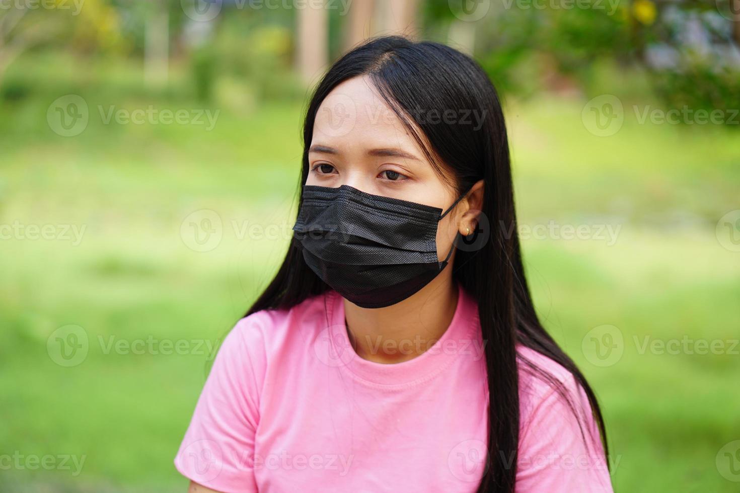 kvinna som bär en mask går i parken. foto