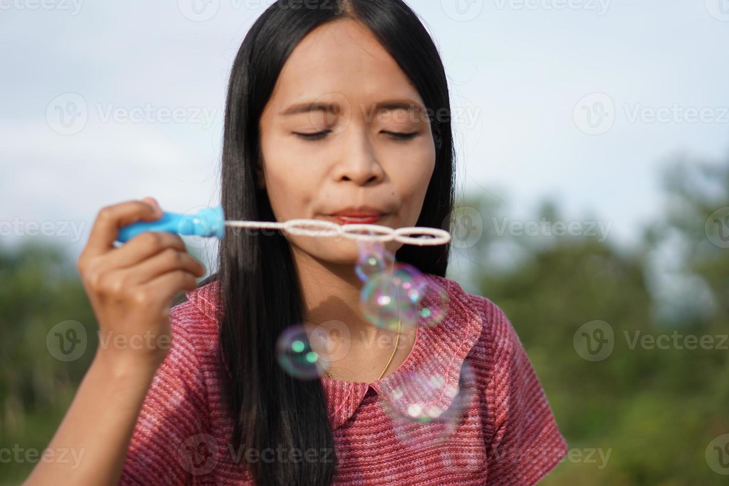 asiatisk kvinna blåser såpbubblor varje grönt gräs bakgrund foto